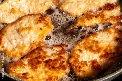 Obraz na płótnie Golden-brown breaded chicken pieces sizzling in hot oil inside a pan. w salonie