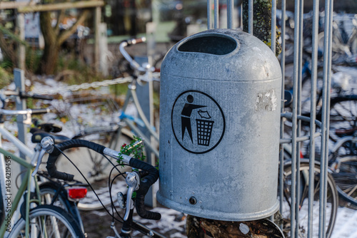 A city bike stands near a trash can. Close-up of the handlebars.