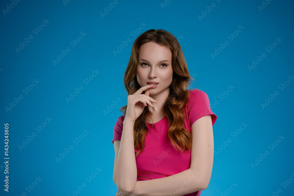 Woman poses in a studio setting with a bright blue background, expressing emotion and confidence through her stance and expression