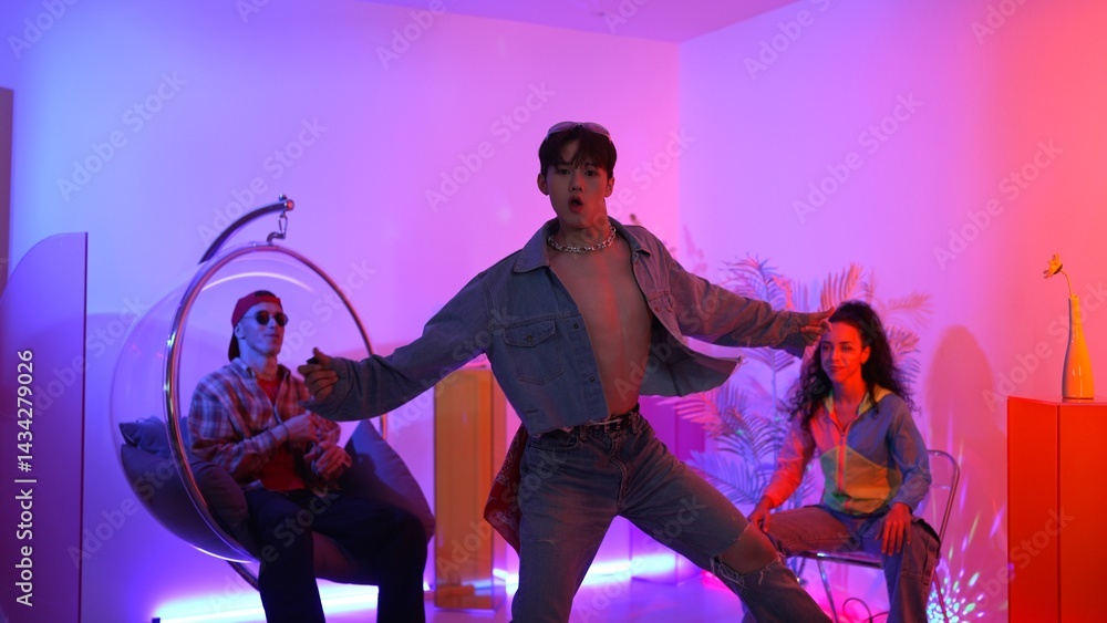 Fototapeta premium Skilled asian dancer moving to modern music while multicultural friend sitting at chair. Professional performer dancing show energetic foot step while hipster team cheering and supporting. Regalement.