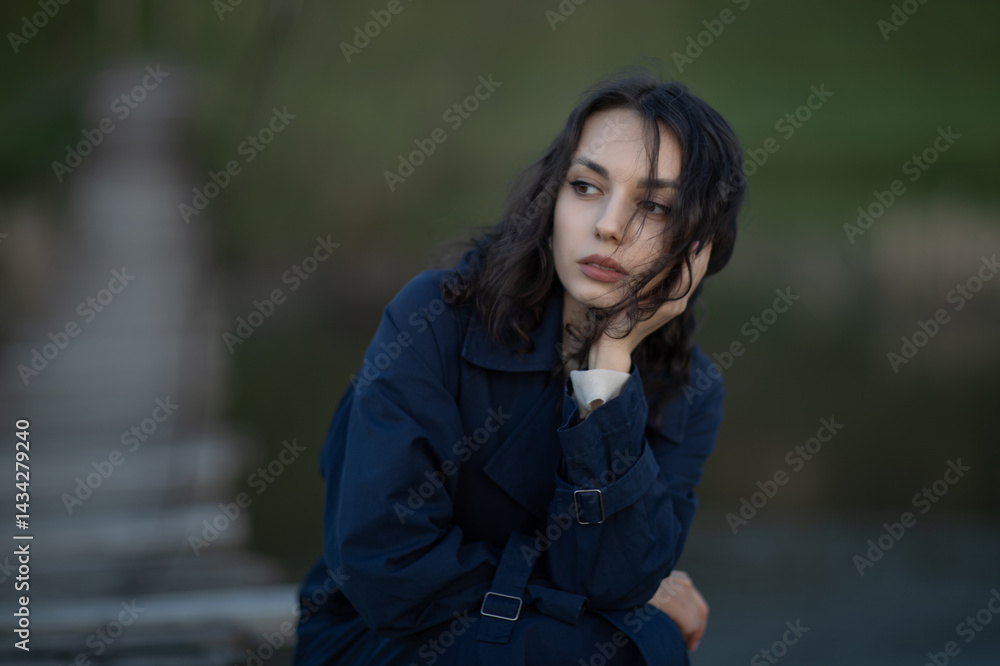 Beautiful brunette meditates sadly in the park in the evening light. Sad girl