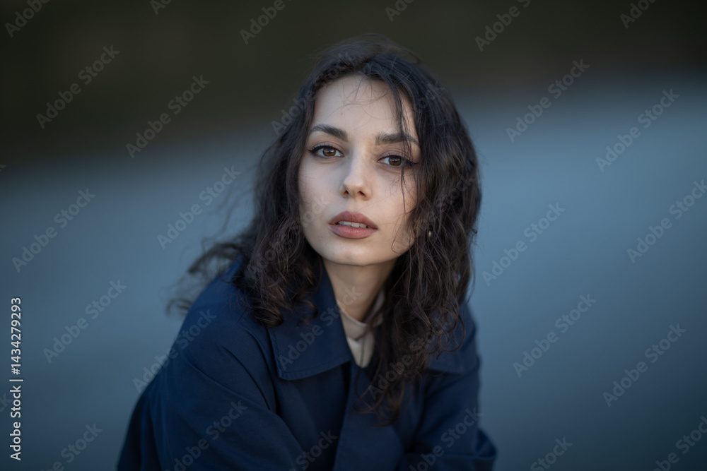 Beautiful brunette meditates sadly in the park in the evening light. Sad girl
