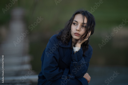 Beautiful brunette meditates sadly in the park in the evening light. Sad girl