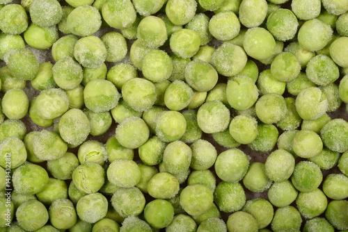 Obraz na płótnie A close-up, top-down shot shows a dense layer of frozen green peas, some with visible ice crystals w salonie