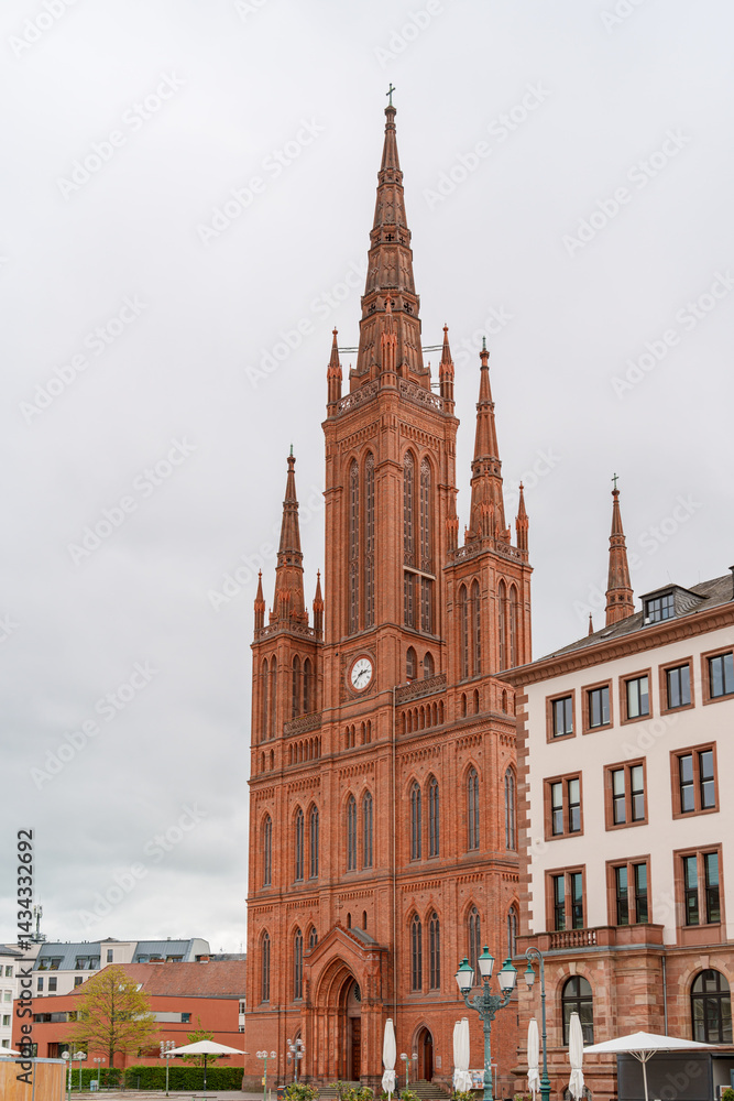 Fototapeta premium A large red building of Market church in Wiesbaden Germany with two tall spires and a clock tower