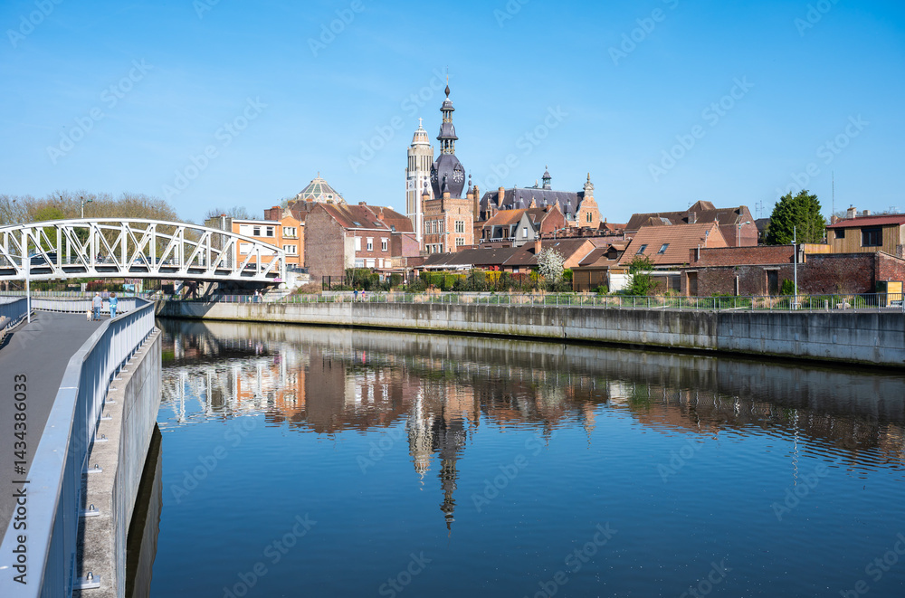 Naklejka premium The French city of Comines Hauts De France reflecting in the river Lys or Leie as seen in Comines - Warneton, Hainaut, Belgium