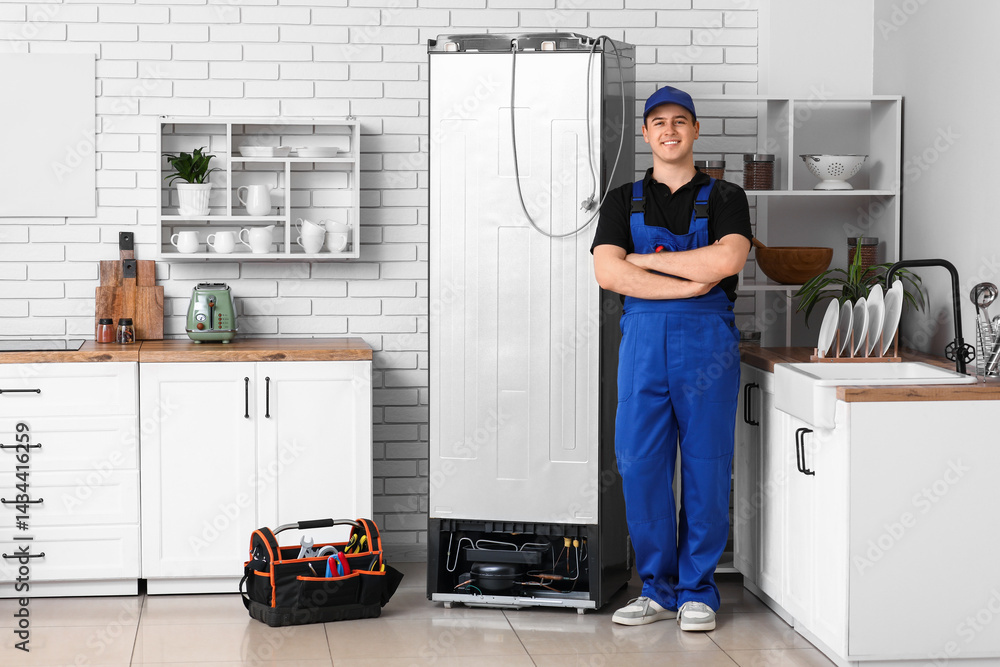 © Pixel-Shot - Happy male worker of repair service with tools near fridge in kitchen