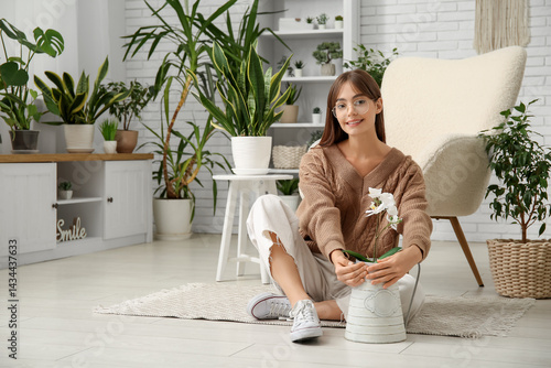 Young female gardener sitti...