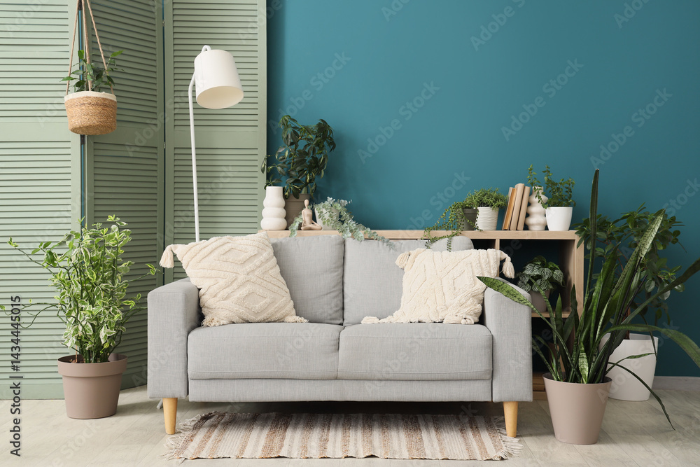 Obraz premium Sofa, lamp, folding screen and houseplants in interior of living room