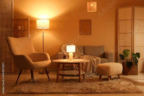 Obraz na płótnie Interior of night living room with sofa, armchair, glowing lamps, folding screen and coffee table w salonie