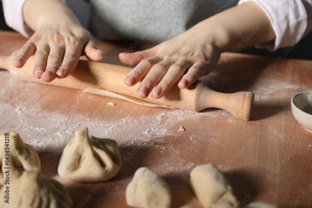 Obraz premium Woman making khinkali on table in kitchen, closeup