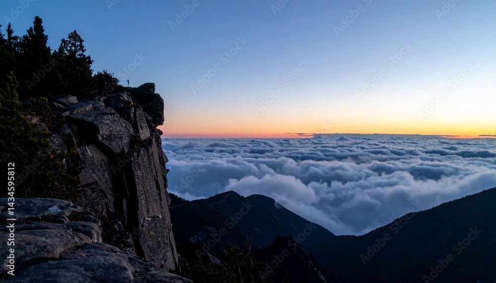 Obraz premium Wide shot from the edge of a mountain cliff at twilight with low clouds rolling in below