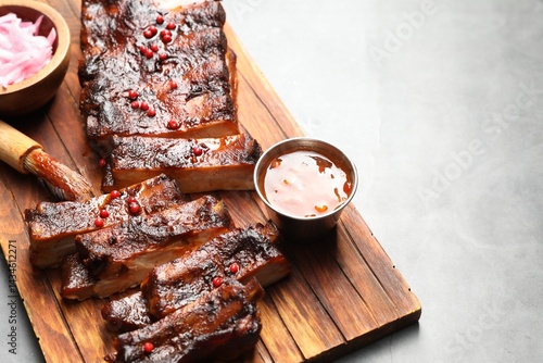 Fotografi Delicious spare ribs, sauce and brush on grey table
