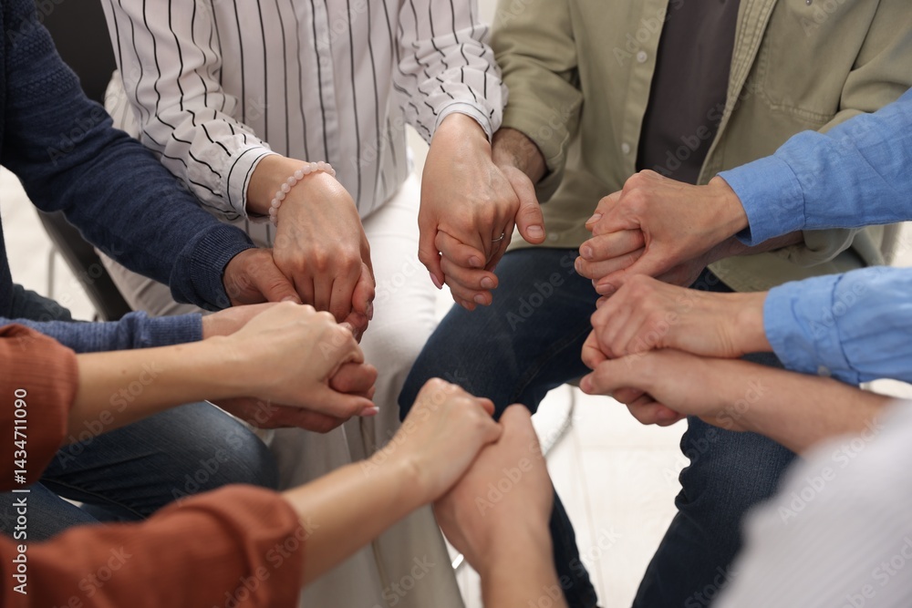 People holding hands during group psychotherapy session indoors, closeup