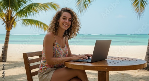 Fototapeta Naklejka Na Ścianę i Meble -  Smiling woman using laptop at table on beach with palm trees and ocean.