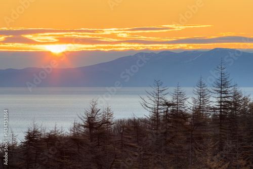 Obraz na płótnie Morning landscape. Sunrise over the sea bay. Larch forest on the coast. Rising sun over the mountains. Autumn season. Nature of Siberia and the Russian Far East. Travel in the Magadan region. Russia. w salonie