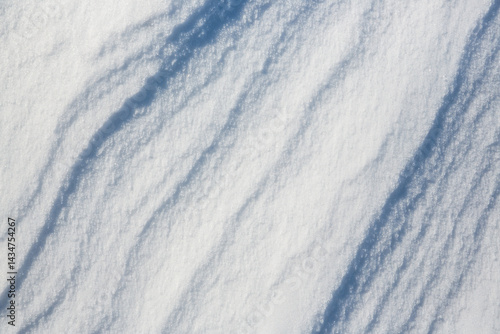Beautiful winter background with snowy ground. Natural snow texture. Wind sculpted patterns on snow surface.