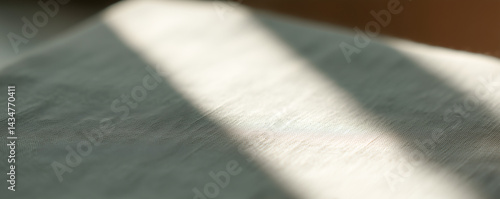 Sunlight creating shadows on soft grey fabric surface