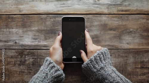 A woman hand interacting with a smartphone on a wooden surface, with plenty of room around the device for customization