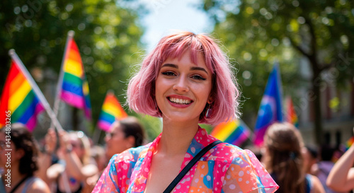 Smiling woman with pink hair at a pride parade surrounded by rainbow flags and other participants