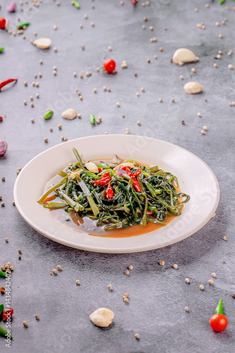 A plate of food with a green vegetable and red peppers on it