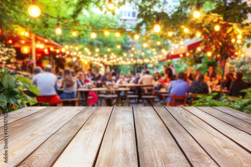 Outdoor dining scene with blurred people enjoying drinks and food. Empty wooden table in foreground