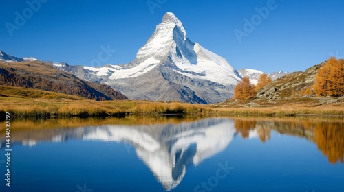 Majestic mountain reflects in calm lake, surrounded by autumnal trees under clear sky