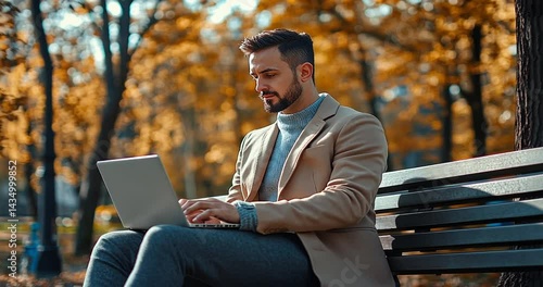 Man working on a laptop in a park surrounded by autumn foliage, showcasing productivity