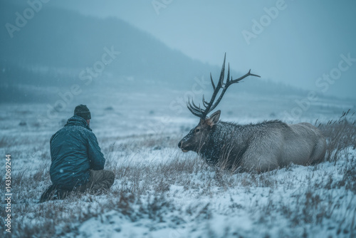 Man kneeling in snow with reindeer, both looking in the same direction, under a soft sunset sky.