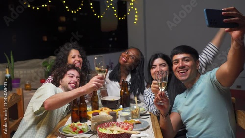group of Latin friends in a terrace, outdoor dinner takes selfie with phone toasting with champagne glasses