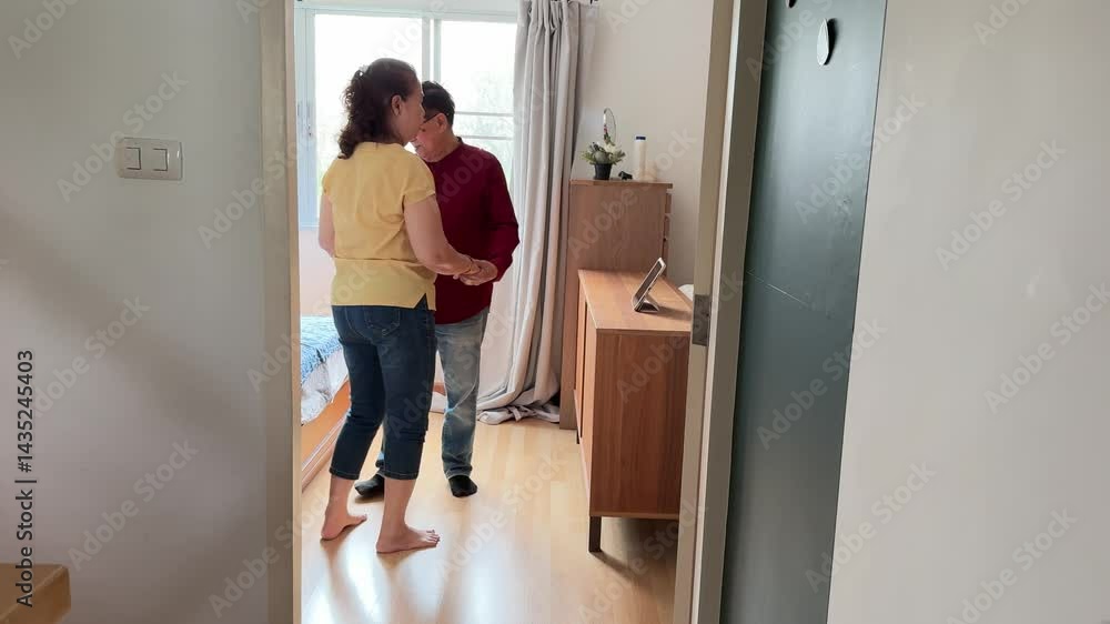 The East Asian senior couple is slow dancing in the bedroom. The East Asian senior couple is slow dancing in the bedroom.