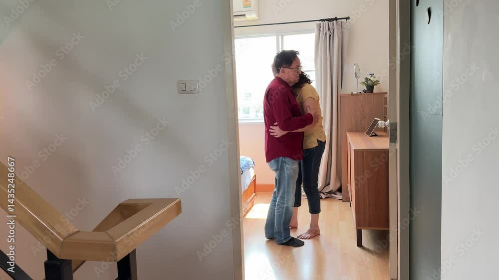 The East Asian senior couple is slow dancing in the bedroom. The East Asian senior couple is slow dancing in the bedroom.