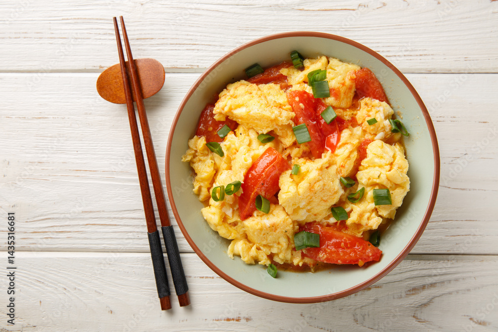 Cantonese Style Tomato Egg Stir-fried with green onion closeup on the plate on the wooden table. Horizontal top view from above