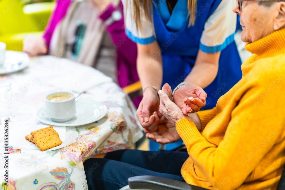 Nurse applying hand cream to elderly woman in nursing home
