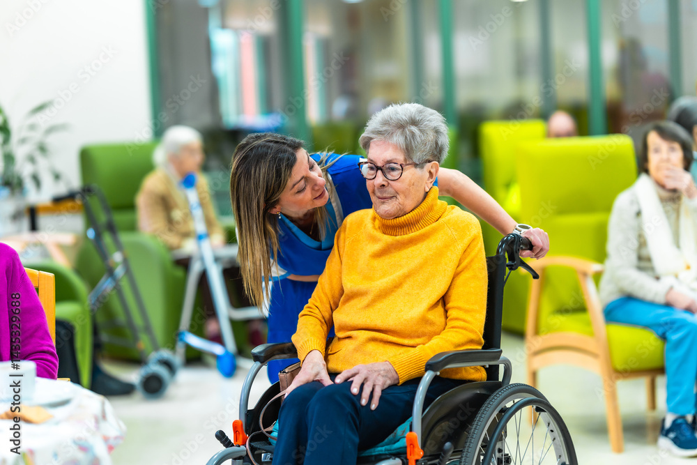 Nurse whispering to elderly woman in wheelchair at nursing home