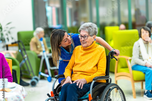Obraz na płótnie Nurse whispering to elderly woman in wheelchair at nursing home w salonie