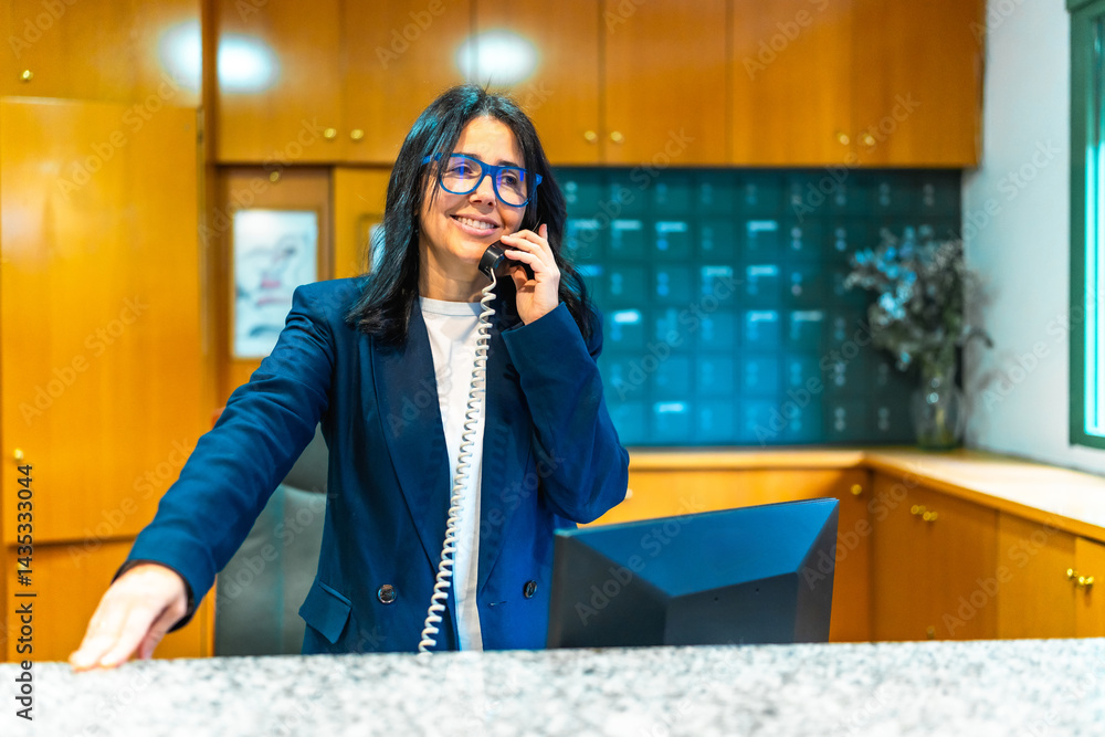 Female receptionist smiling and speaking on the phone at nursing home reception