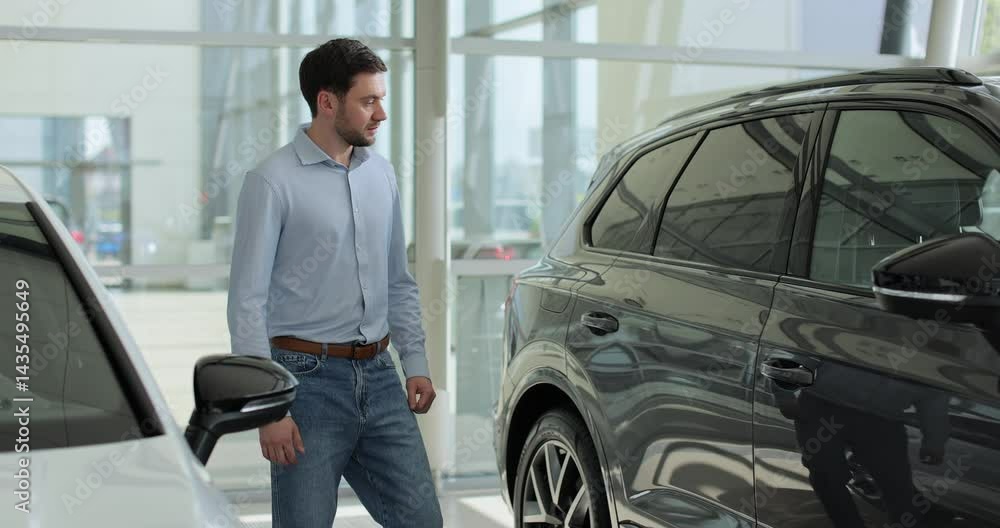 Handsome man touching new car in showroom. Concept of car shopping, buying, and dealership. Handsome man touching new car in showroom. Concept of car shopping, buying, and dealership.