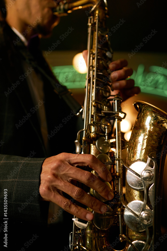 Fototapeta premium Vertical close up on saxophonists fingers playing brass instrument creating jazz music during live performance in dimly lit bar