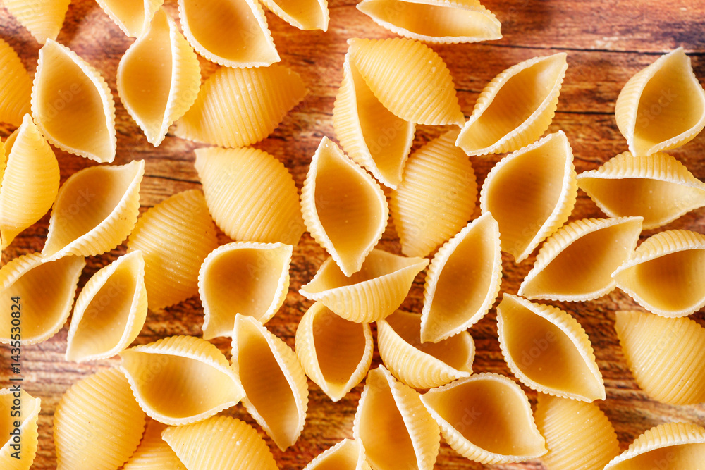 Raw uncooked dried Conchiglie shell pasta. Italian seashells pasta on wooden background. Raw uncooked dried Conchiglie shell pasta. Italian seashells pasta on wooden background.