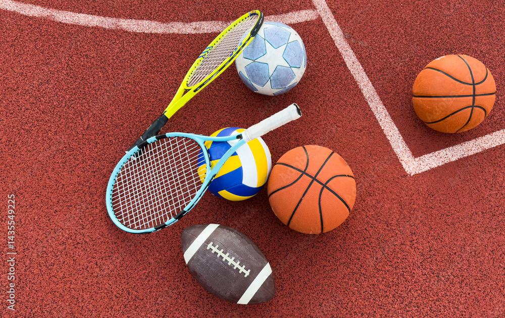 A variety of sports equipment including an american football, a soccer ball, a tennis racket, a tennis ball, and a basketball