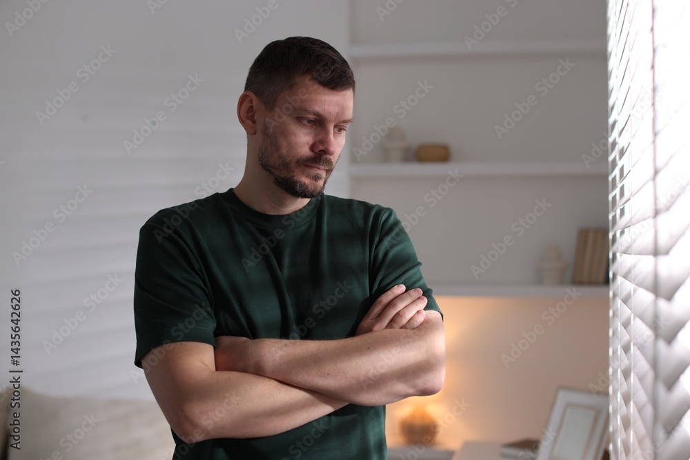 Depressed man looking out window at home Depressed man looking out window at home