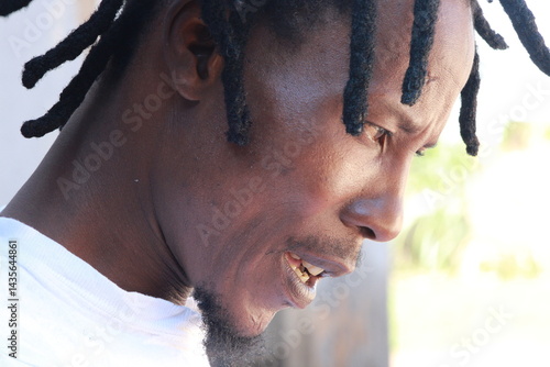 African Man with dreadlocks in a hair salon plaited by a young African lady