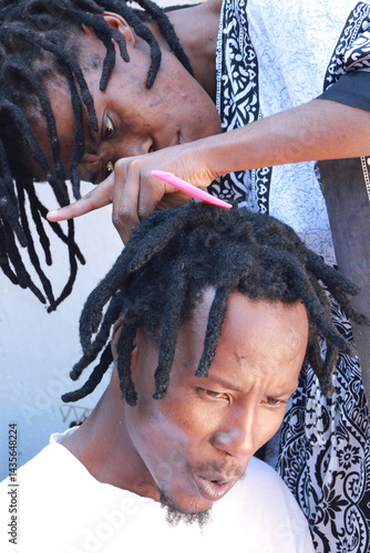 young african rasta lady doing dreadlocks to her african rasta man