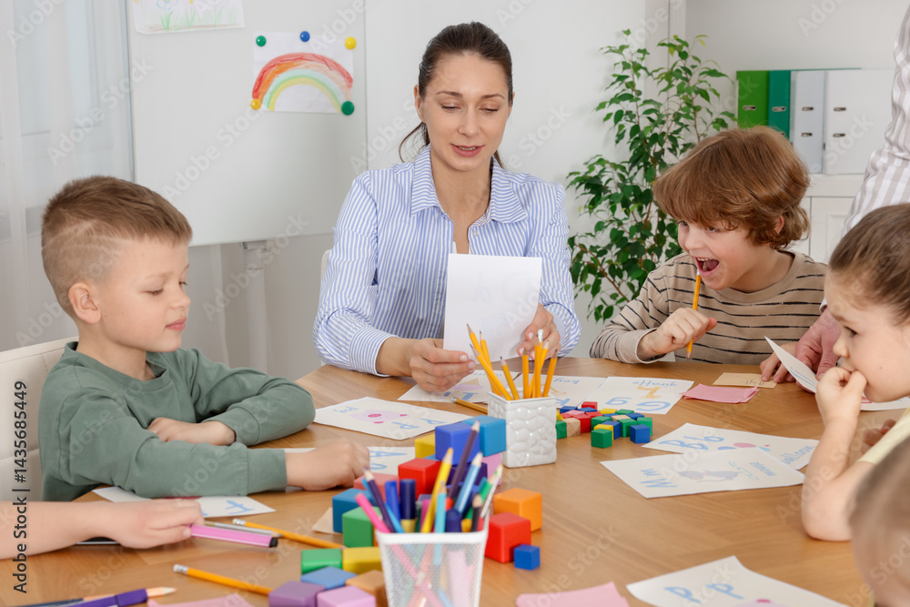 Fototapeta premium Children having lesson with teacher at desk indoors