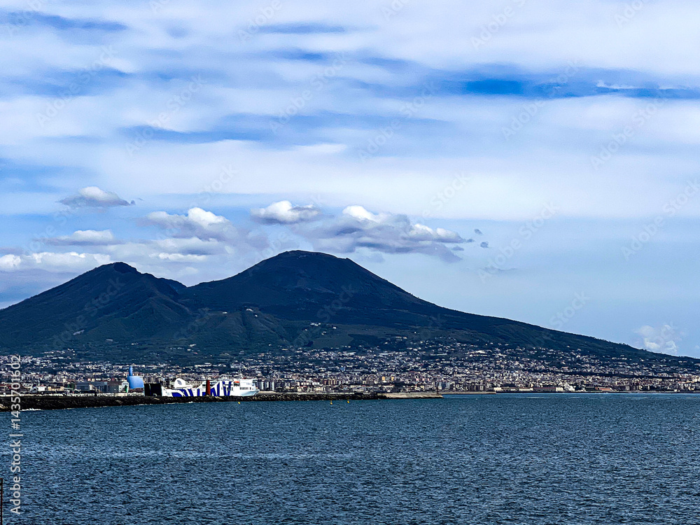 A massive mountain rises from the deep blue sea under a sky with scattered clouds. The rugged peak contrasts with the calm water, capturing a dramatic coastal scene., vesuvio, naples, napoli, napoles A massive mountain rises from the deep blue sea under a sky with scattered clouds. The rugged peak contrasts with the calm water, capturing a dramatic coastal scene., vesuvio, naples, napoli, napoles