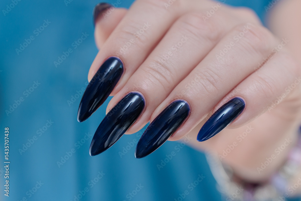 Woman's beautiful hand with long nails and dark blue manicure