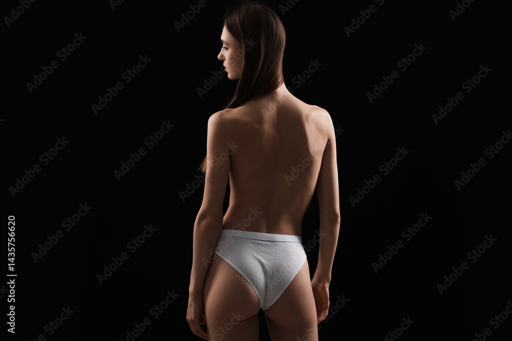 Naklejka premium Woman in panties on black background, back view