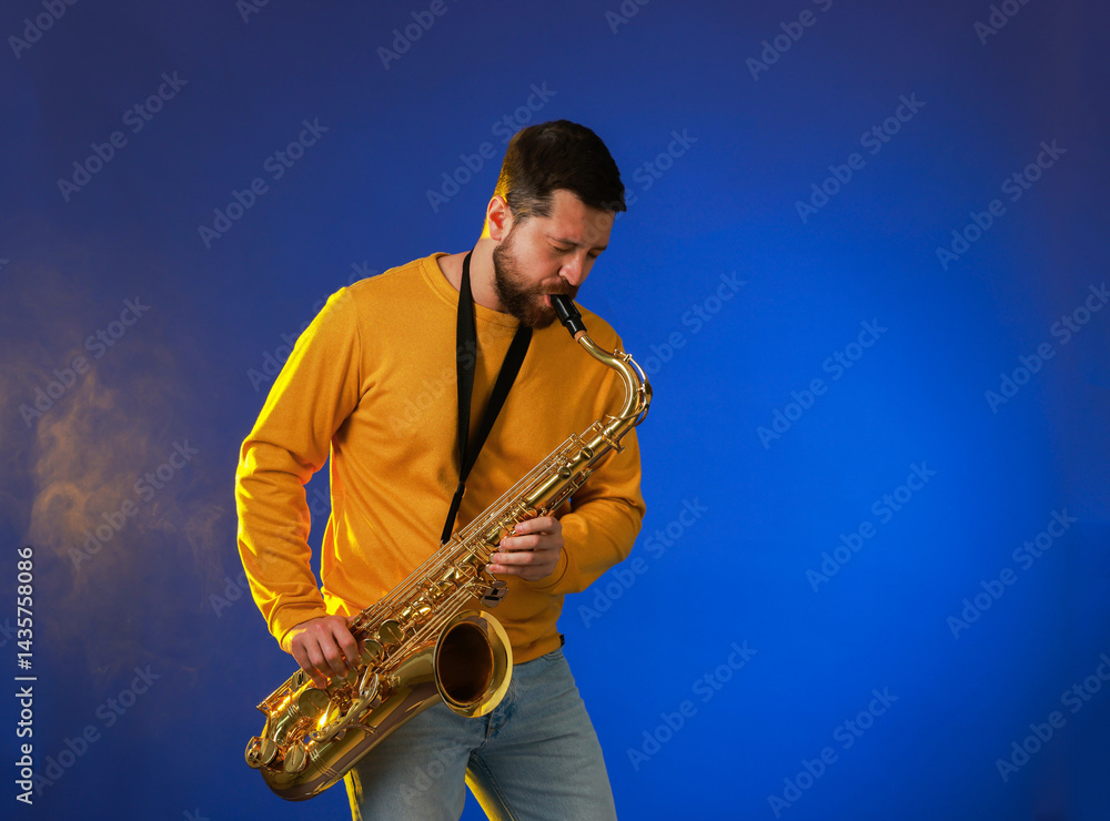 Fototapeta premium Professional musician playing saxophone on blue background