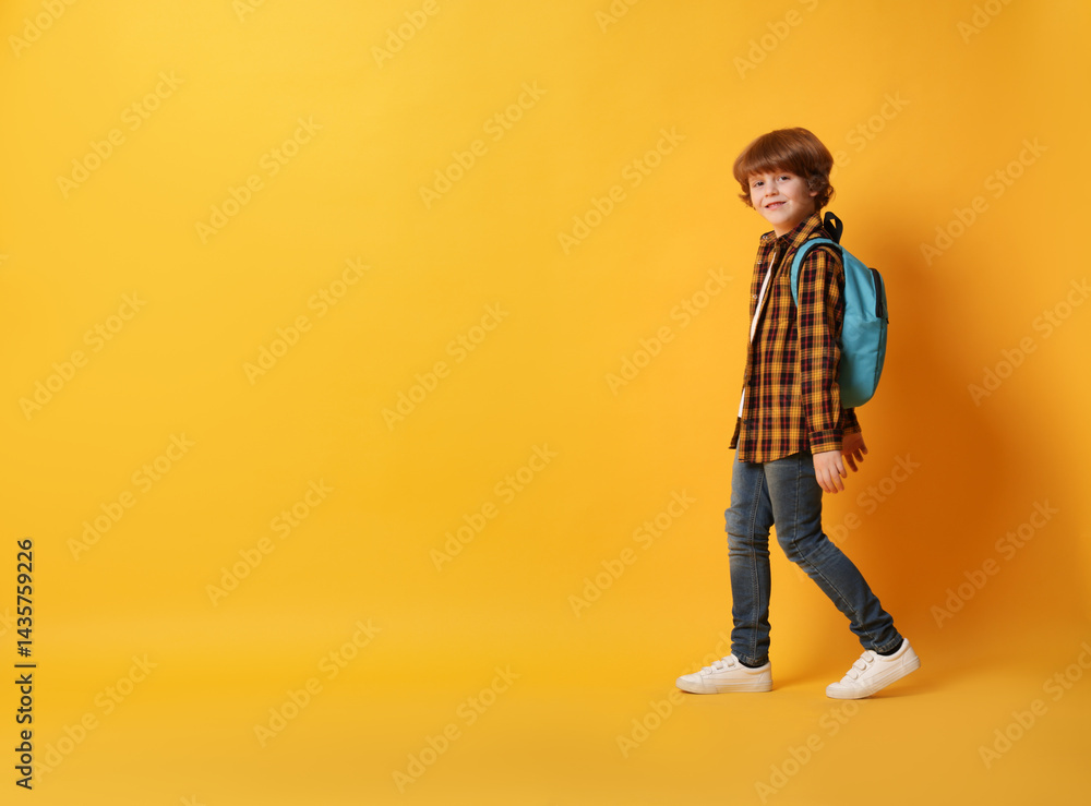 Cute schoolboy with backpack on orange background, space for text Cute schoolboy with backpack on orange background, space for text